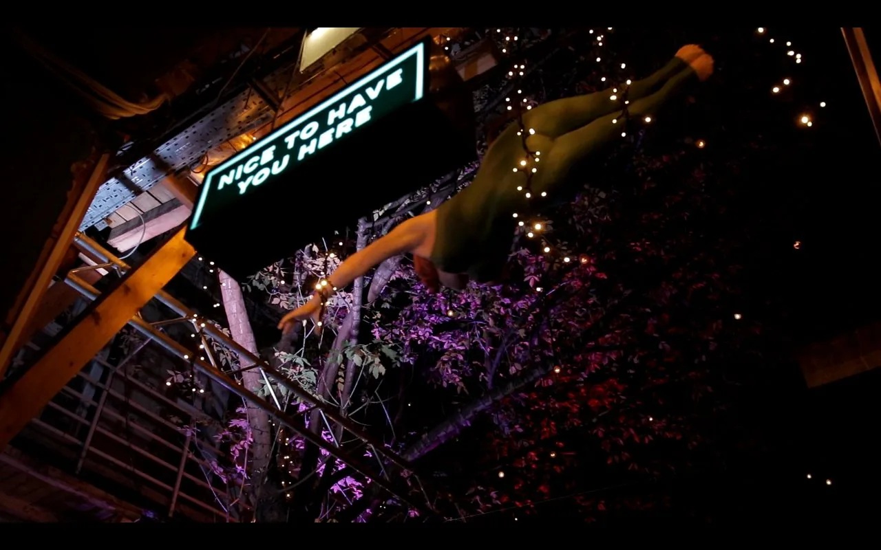 A glowing 'Nice to have you here' neon sign among fairy-lit trees at Instant-Fogas, Budapest's biggest ruin-bar complex